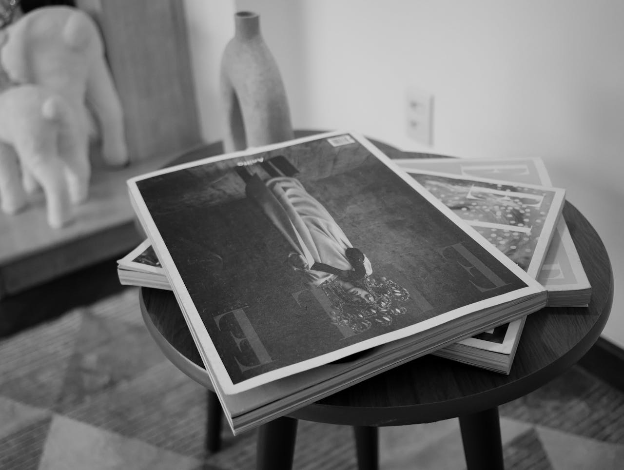 Monochrome image of fashion magazines on a table in a stylish interior setting.
