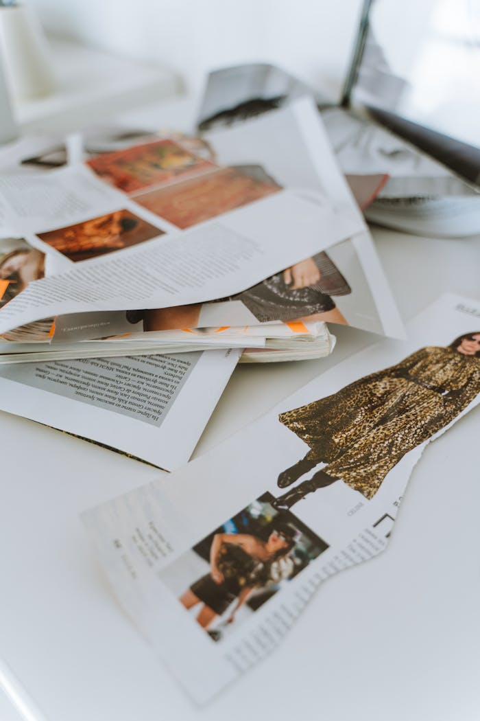 A close-up of torn fashion magazine pages on a desk, showcasing creativity.